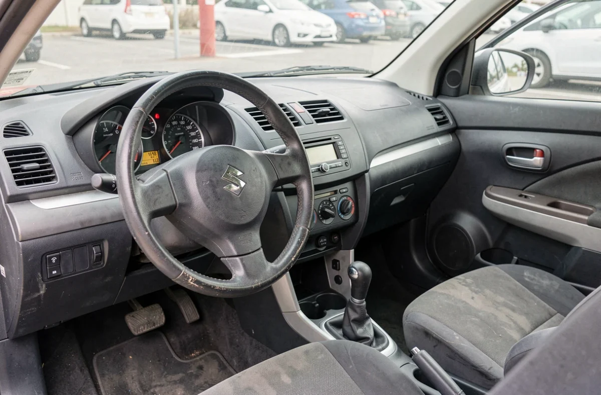 Tableau de bord intérieur d'une Suzuki Swift 1.3 DDiS avec kilométrage élevé, illustrant l'usure typique d'une voiture fiable au quotidien