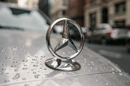 Gros plan sur l'emblème étoile à trois branches de Mercedes-Benz sur le capot d'une voiture de luxe, avec des gouttelettes d'eau sur le chrome poli