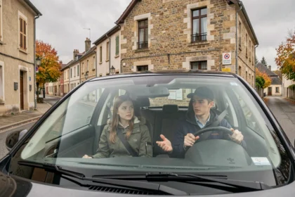 Scène d'auto-école en Haute-Saône avec un instructeur et un élève dans un véhicule à double commande dans une rue pavée française